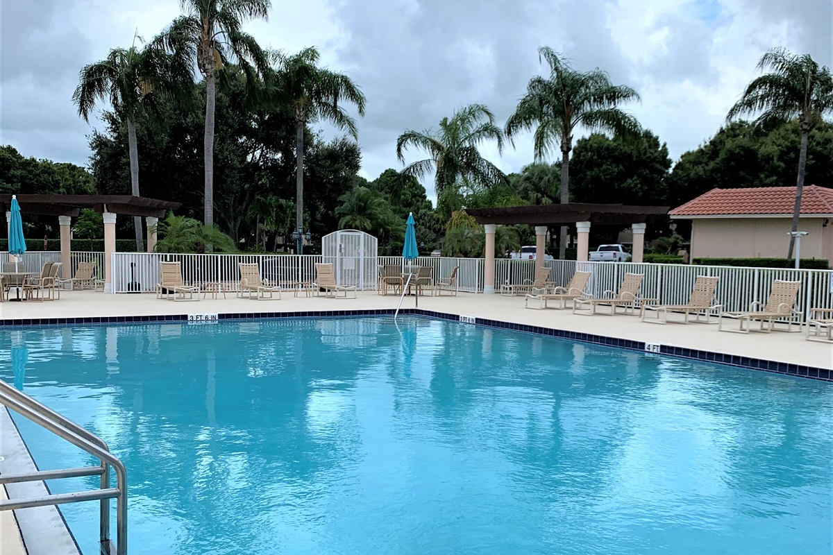 Bright community pool area with lounge seating, umbrellas, and a relaxing resort-style atmosphere.