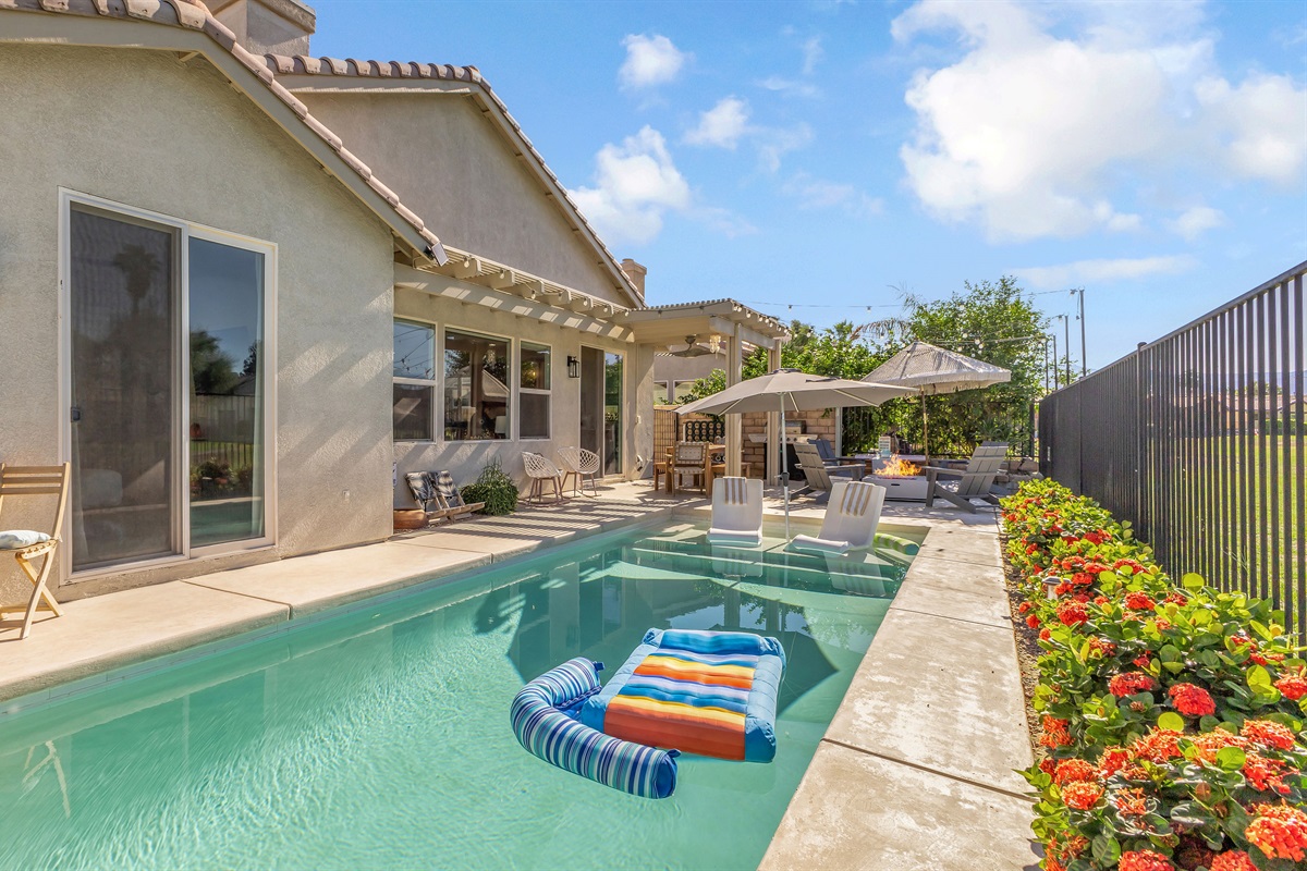 🌅 Sunlit Backyard Oasis  This sunny backyard retreat features a sparkling pool, shaded patio, and open views—ideal for morning coffee or sunset cocktails.