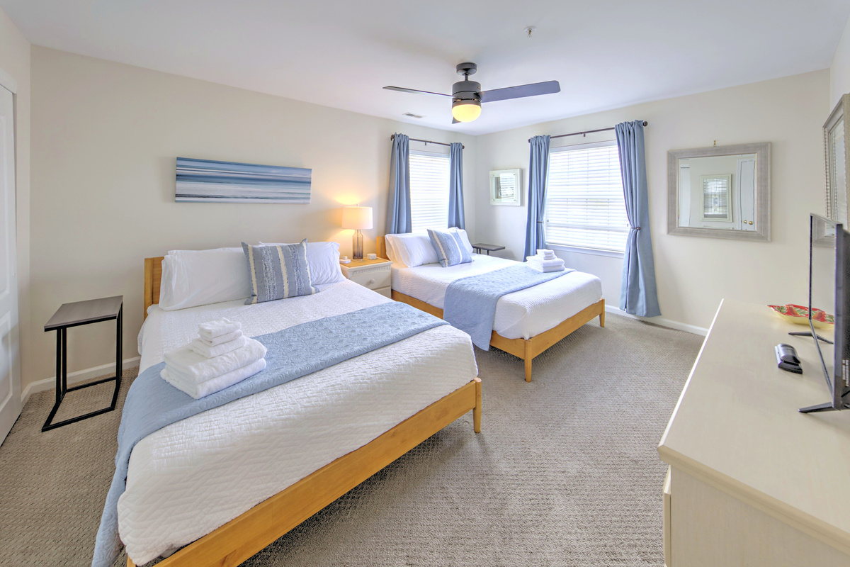 Fresh linens provided and beds professionally made before arrival—no linen rentals required.

Bedroom 2: Bright and airy retreat with two queen beds and serene coastal decor!