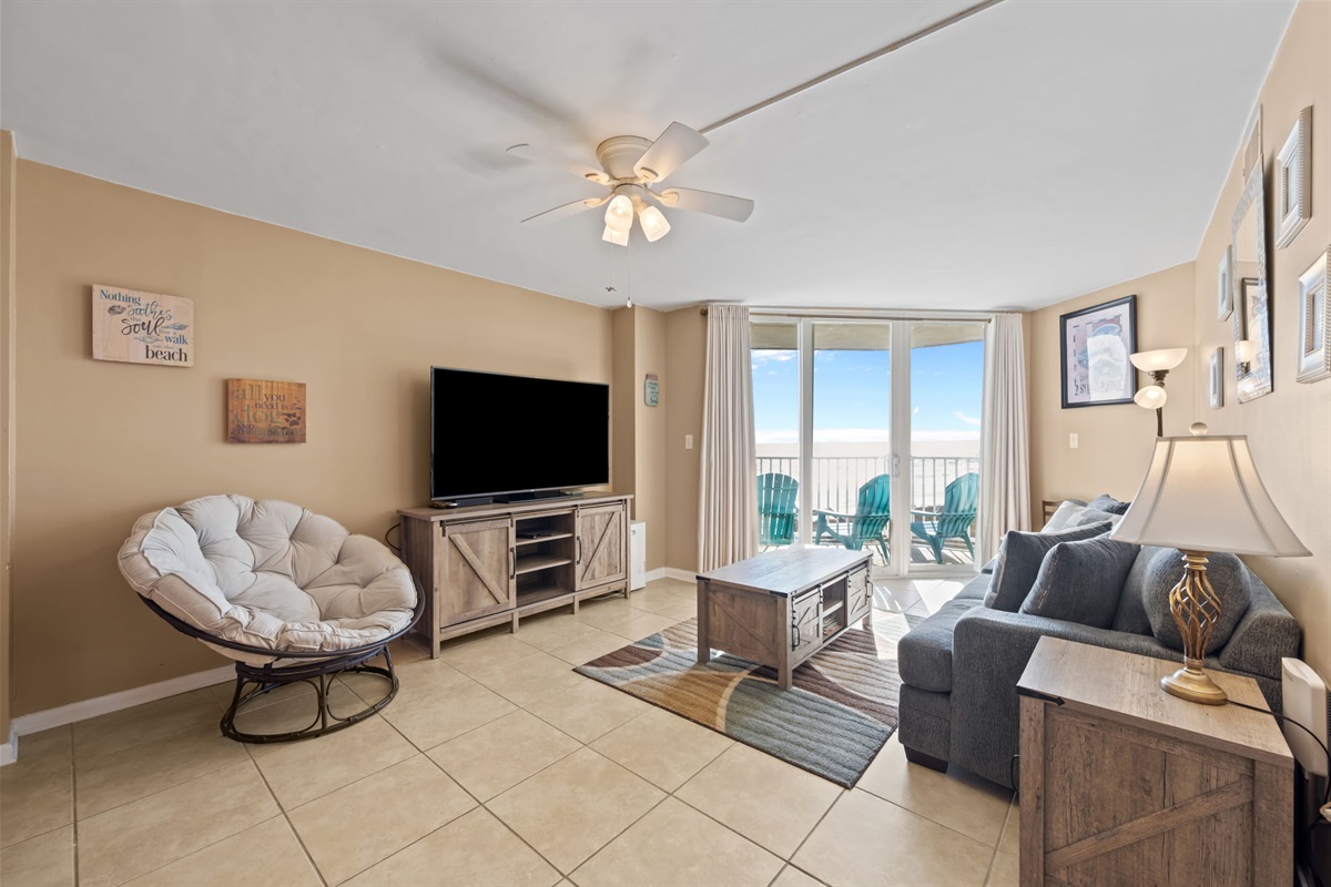 Open-concept living area featuring a plush sofa, cozy lounge chair, and plenty of natural light from the oceanfront balcony