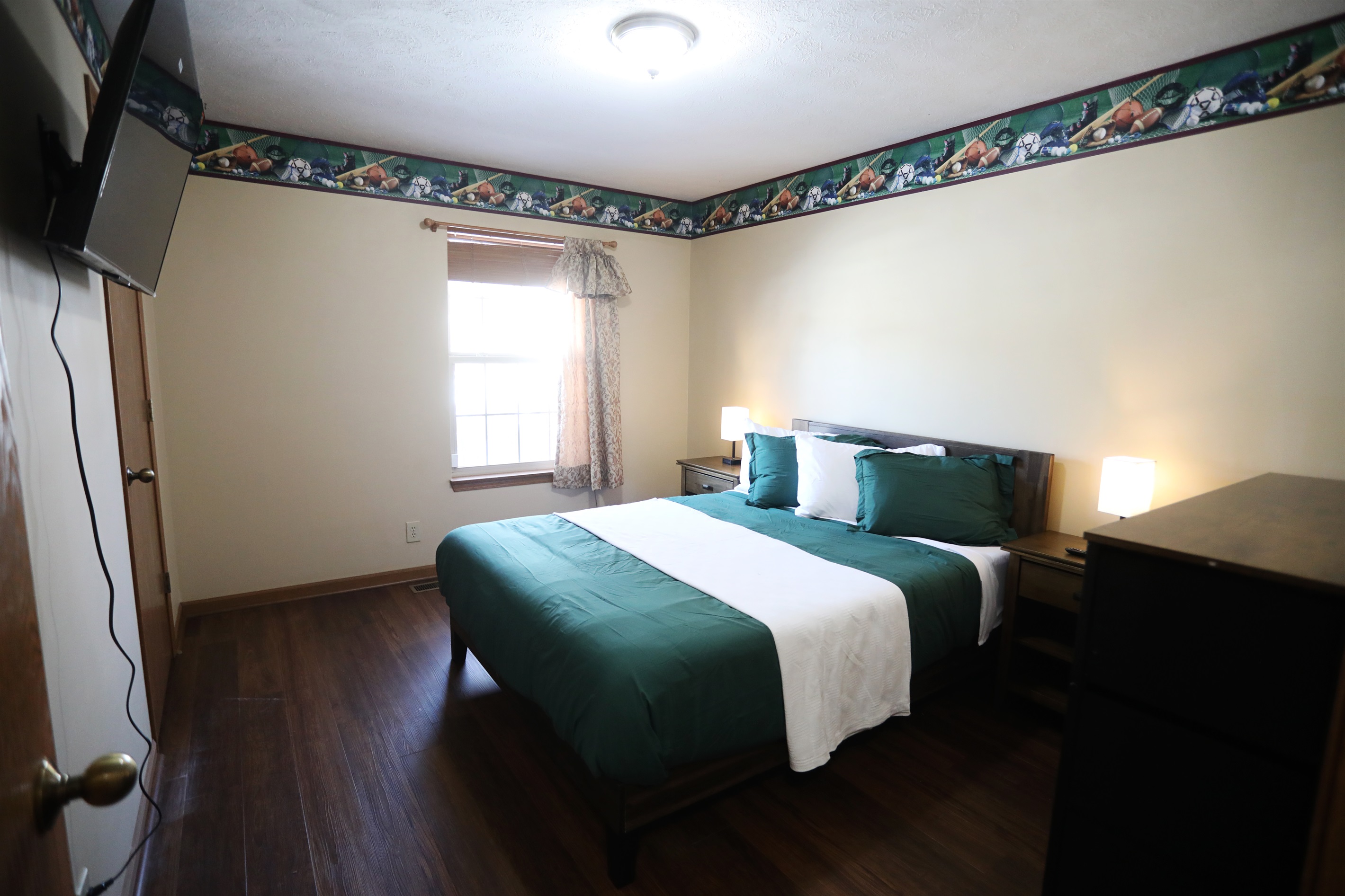 SE bedroom showing showing queen size bed, Roku TV, dresser, nightstands with touch lamps, and alarm clock