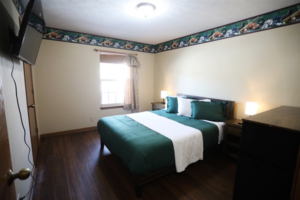 SE bedroom showing showing queen size bed, Roku TV, dresser, nightstands with touch lamps, and alarm clock