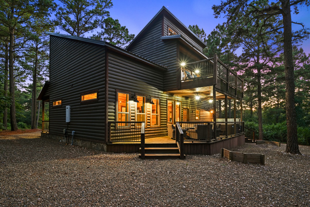 Evening glow lights up the modern architecture and wraparound porch, creating a perfect mountain escape.