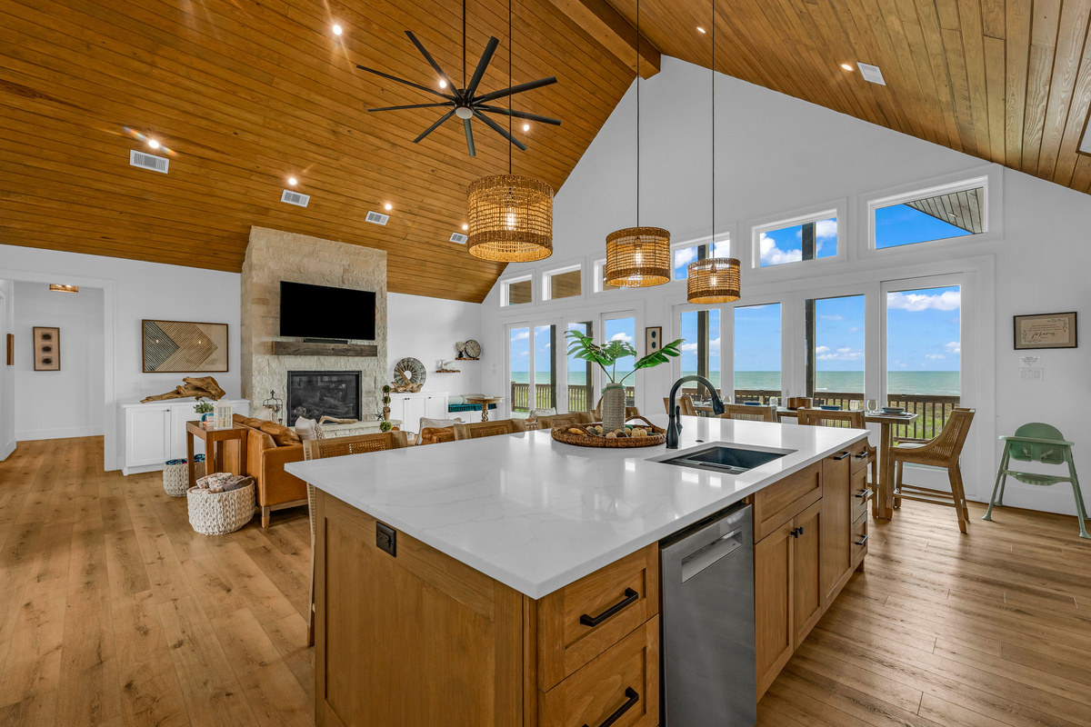Cair Paravel: The kitchen opens directly to the living area's stone fireplace and out to the covered deck beyond, creating an effortless flow for entertaining a full house.