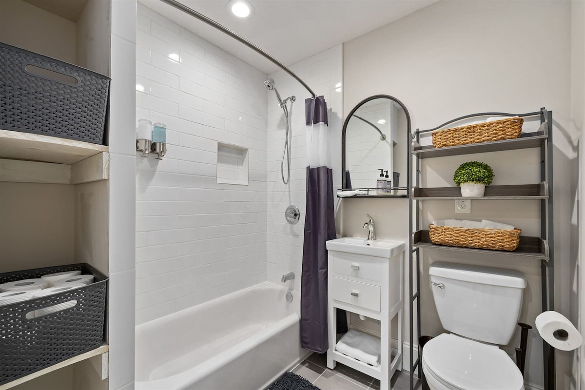 Spacious bathroom featuring a tub, fresh towels, and ample storage.