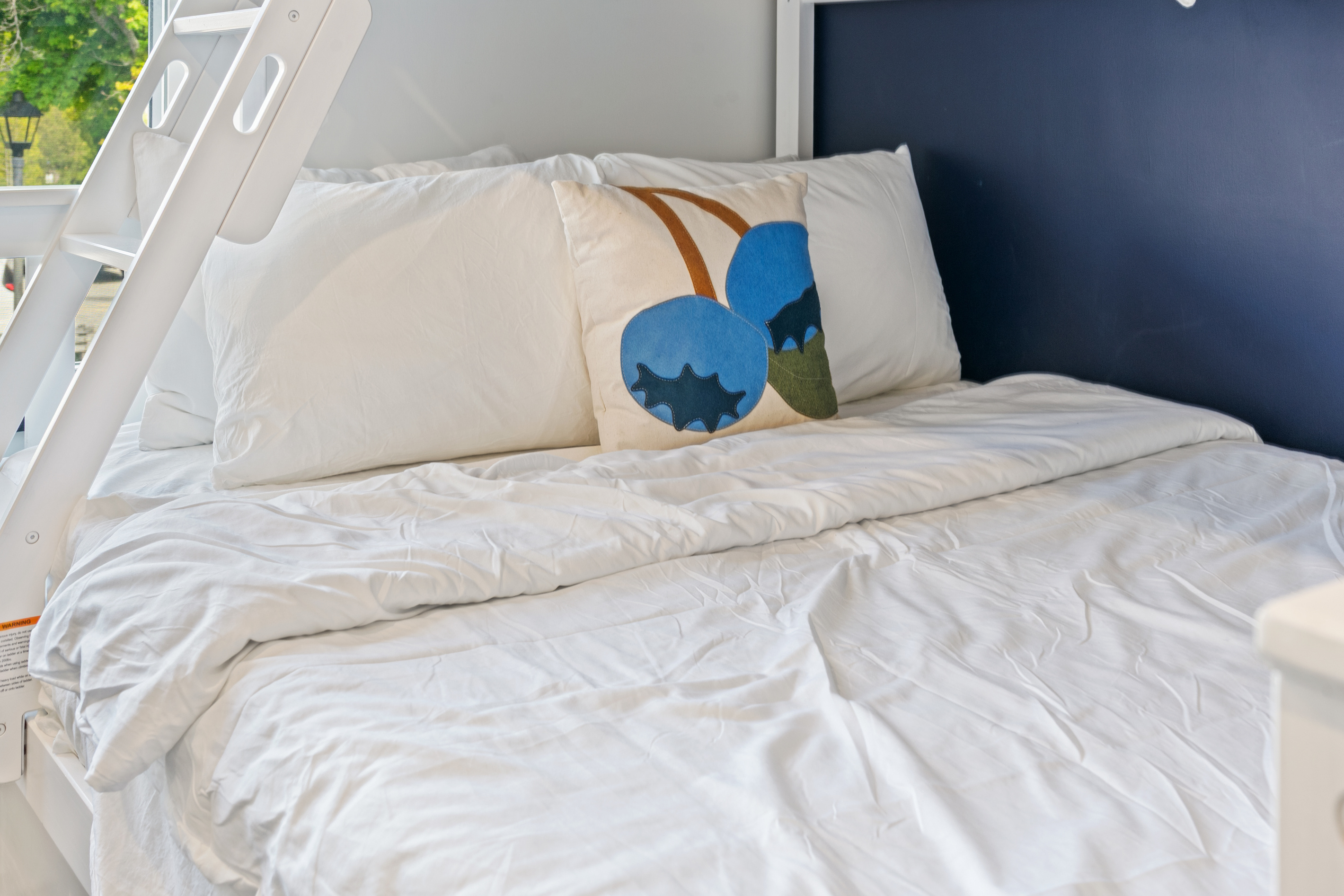 A classic Down East Maine touch in the family-friendly bunk room. The bottom Double mattress features crisp white linens, a comfortable duvet, and a custom blueberry accent pillow. Located right in the heart of downtown Bar Harbor.