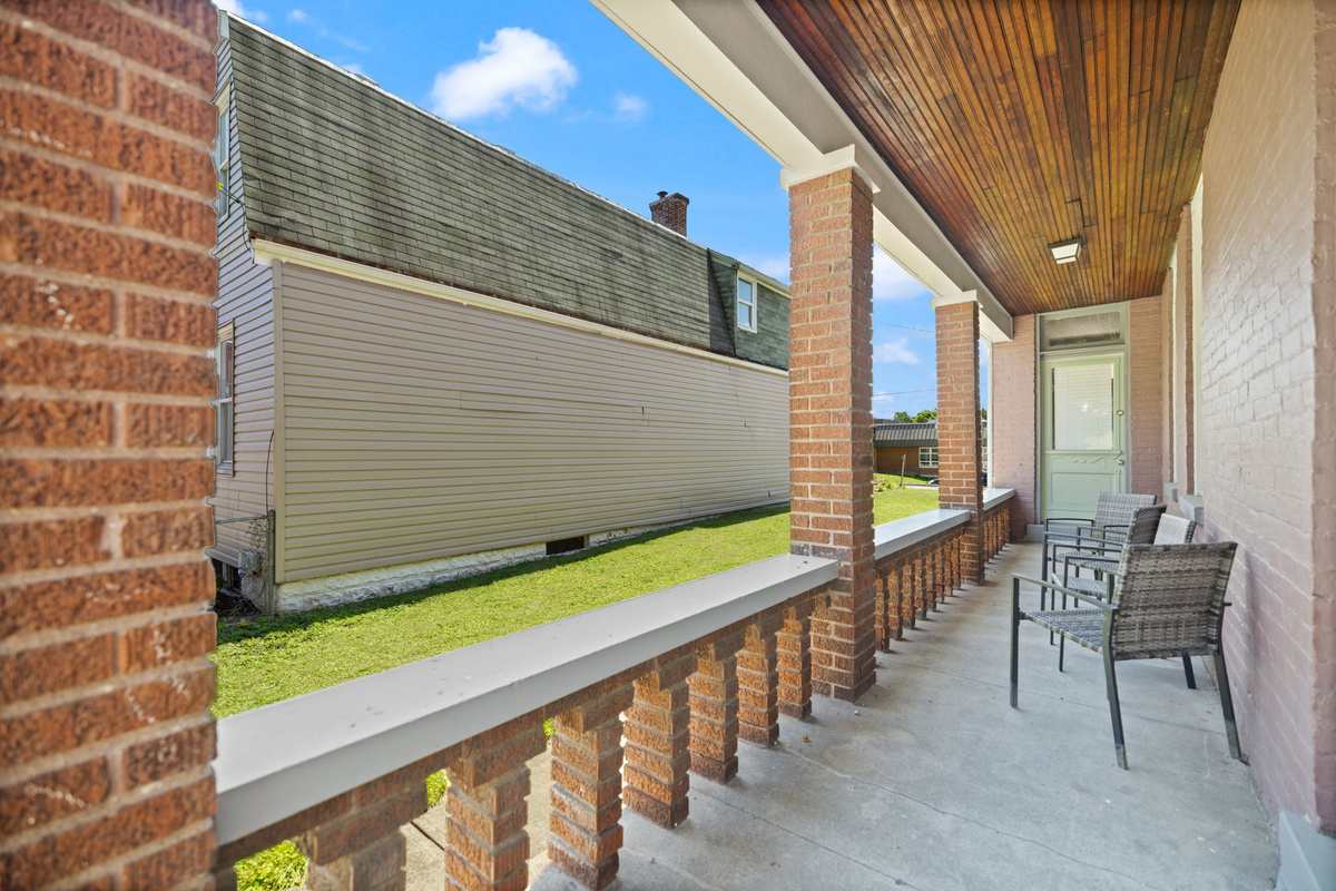 Covered brick porch with outdoor seating. Perfect for a relaxing evening.