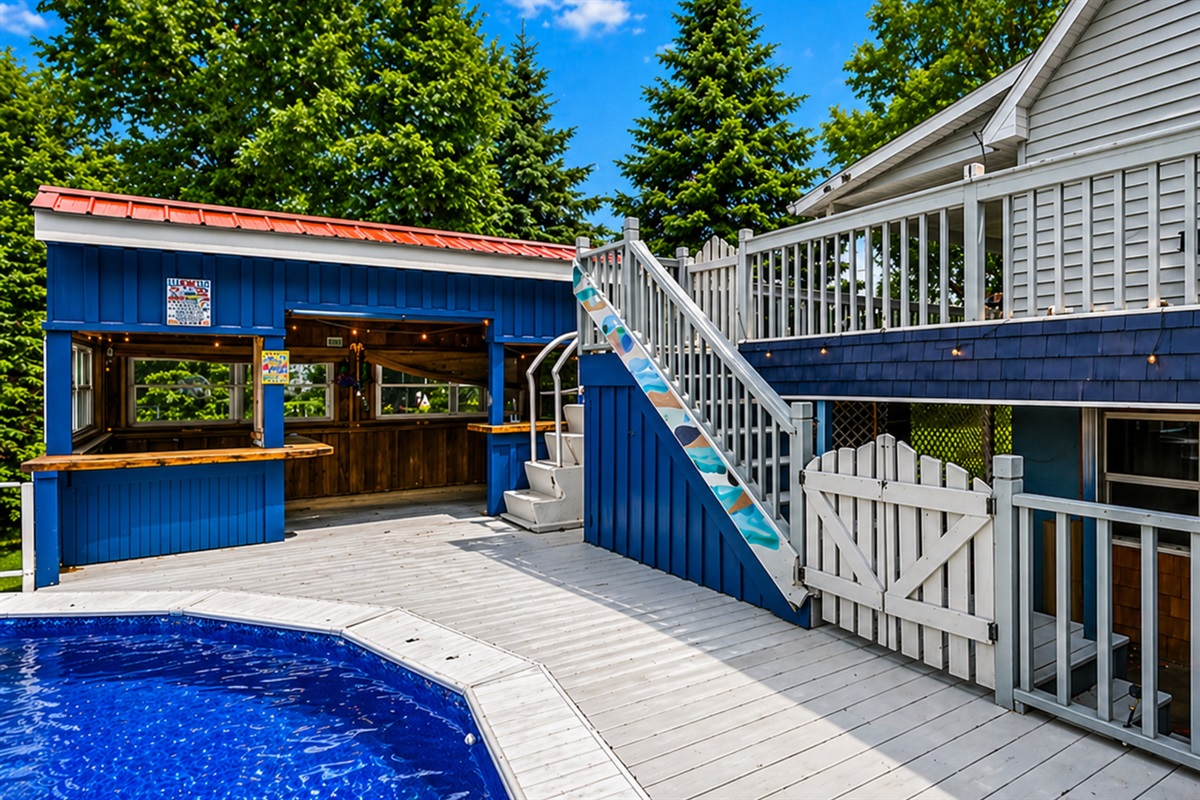 This vibrant outdoor area features a spacious deck, a refreshing pool, and a charming poolside bar, perfect for entertaining.
