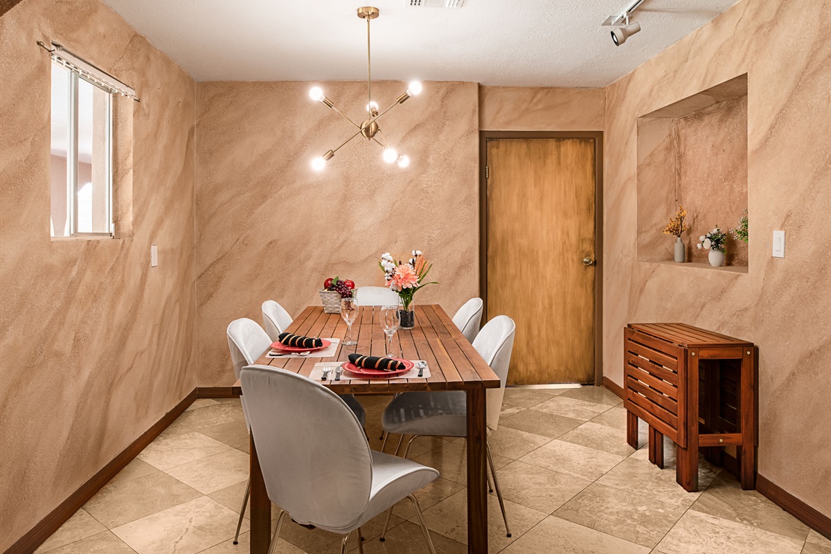 Gather for meals or game nights in this stylish dining room, featuring warm textured walls, modern lighting, and a cozy, intimate atmosphere.