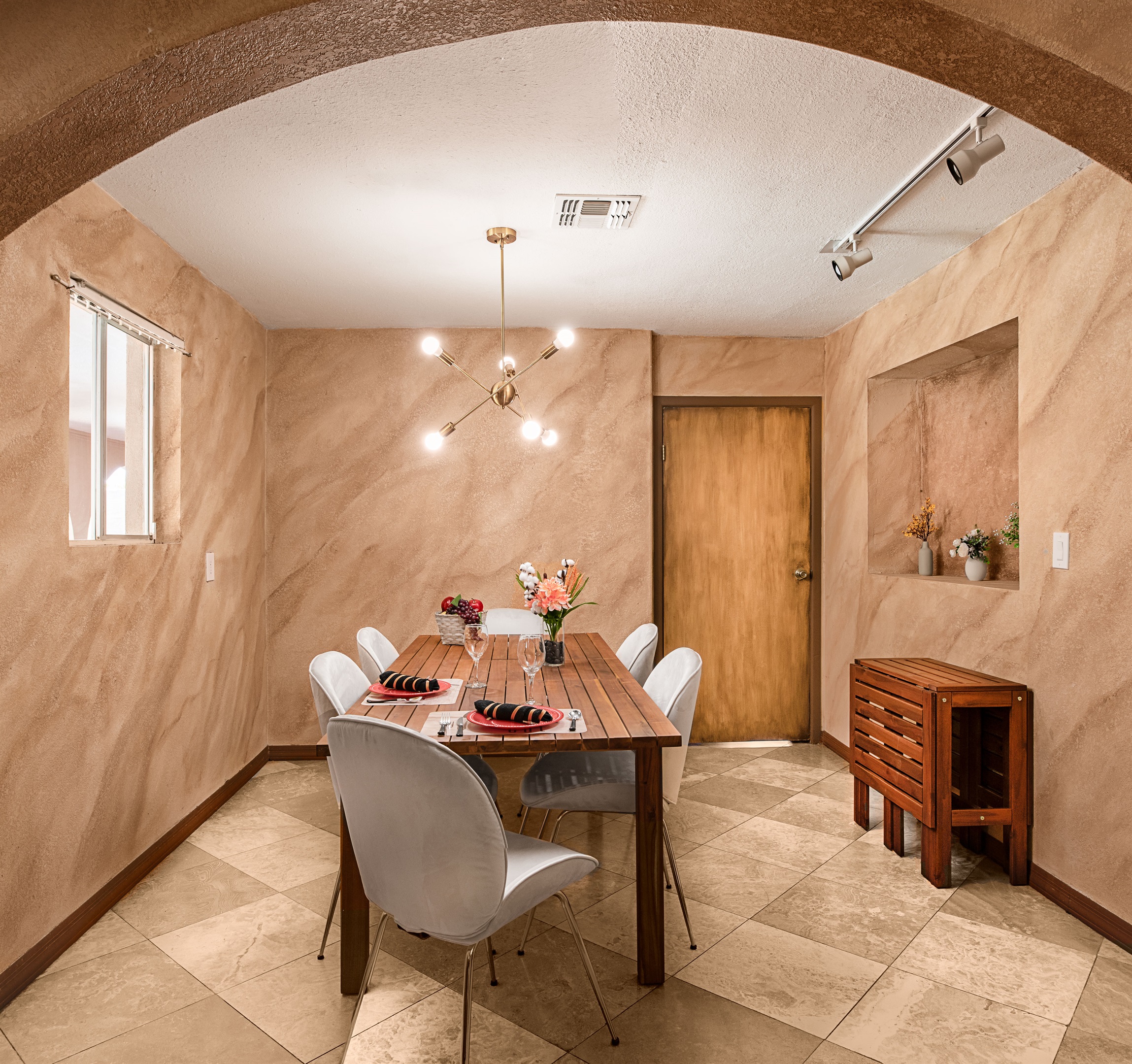 Gather for meals or game nights in this stylish dining room, featuring warm textured walls, modern lighting, and a cozy, intimate atmosphere.