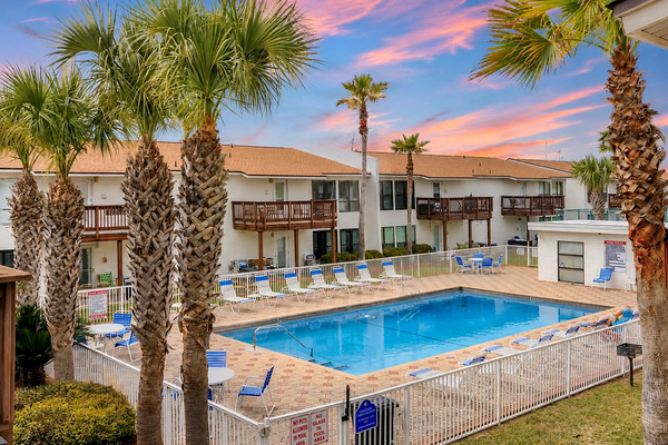 Poolside Paradise at Navarre Beach. Palm-lined pool deck just steps from your door, with loungers, patio seating, and a private grill area. The perfect spot to unwind between beach trips.