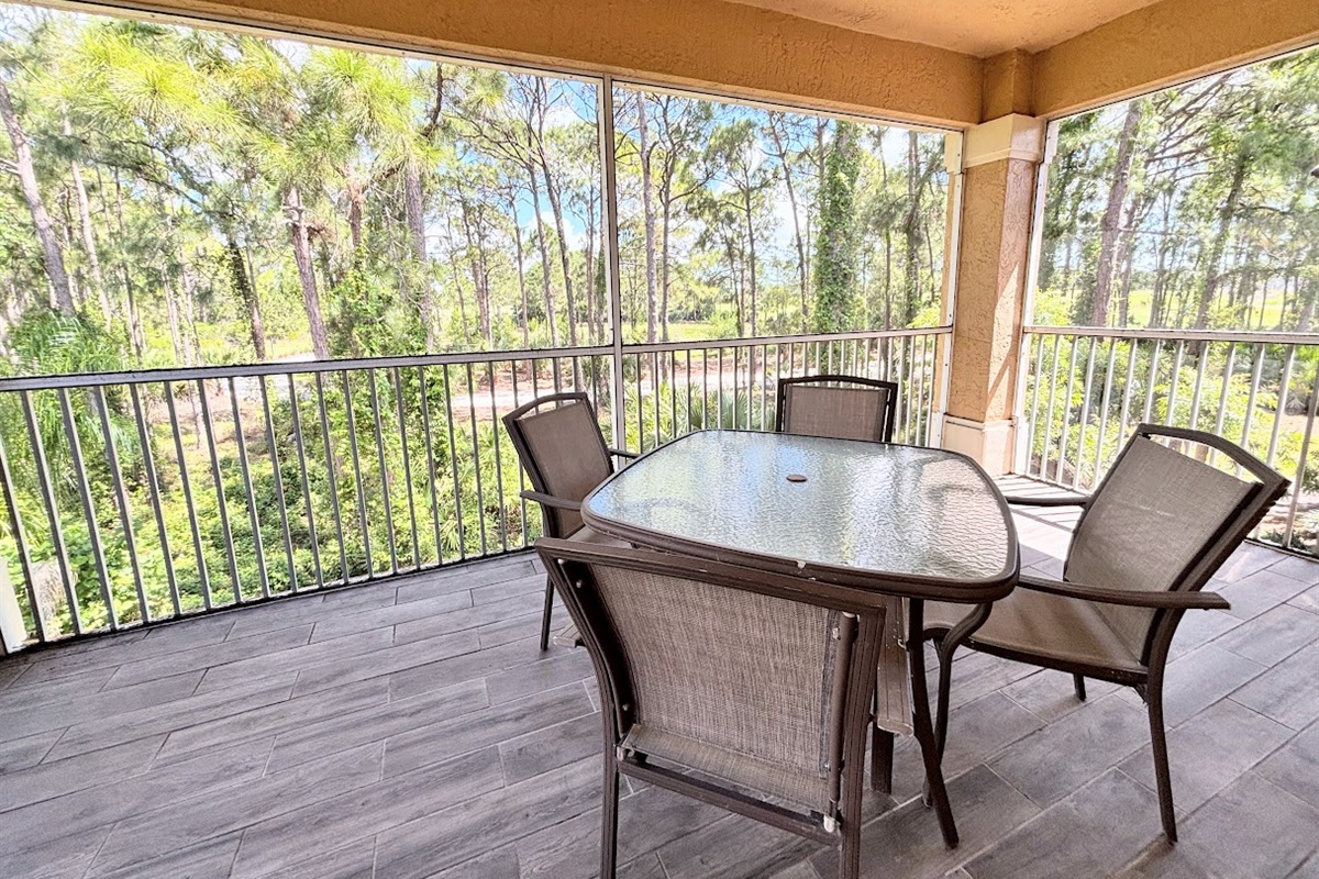 Private screened balcony with outdoor dining space and peaceful views of the surrounding trees.
