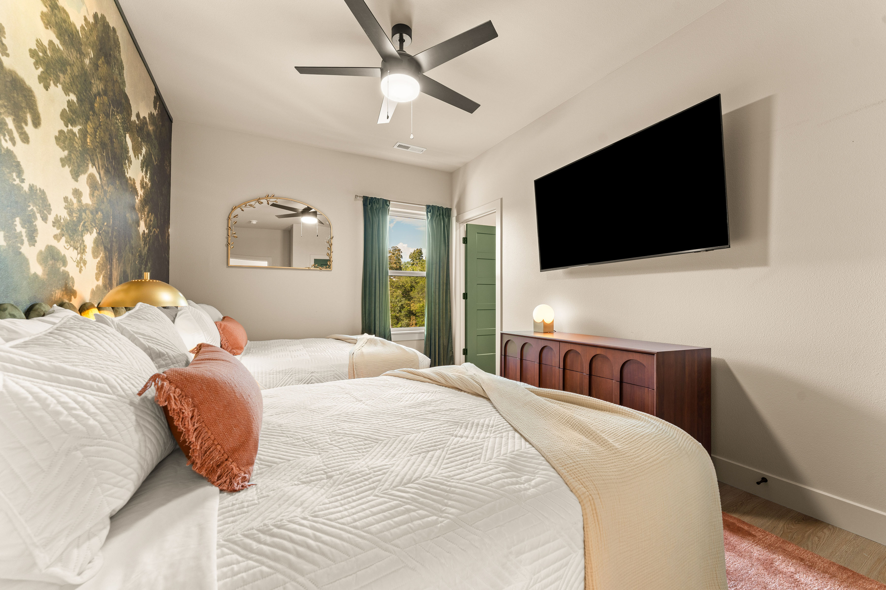 A dramatic woodland mural, plush king bed, and warm designer details create a peaceful retreat after a day exploring Branson.