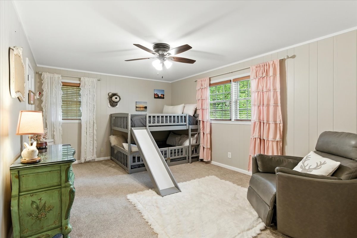 This upstairs bedroom features double full-size bunk beds, a cozy rocking chair, and a spacious walk-in closet.