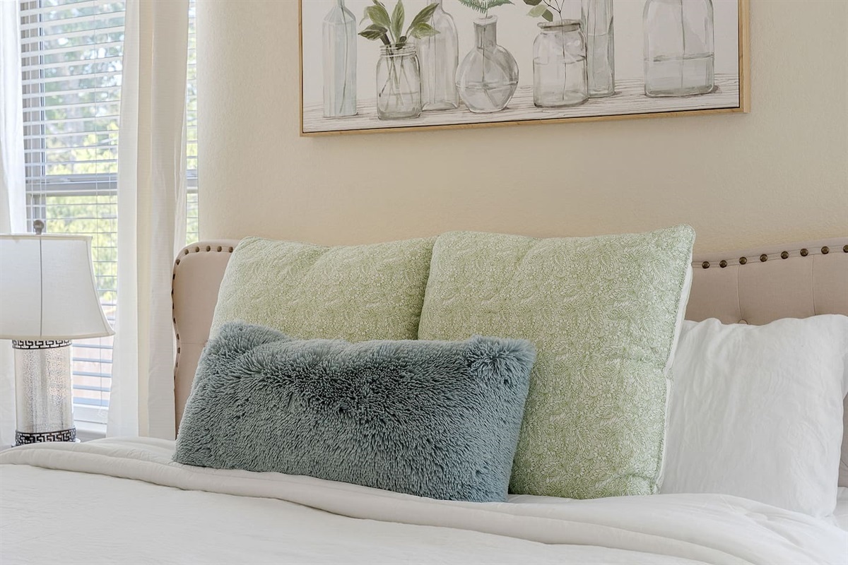 Step inside a serene bedroom featuring a cozy bed, stylish bedside lighting, and subdued botanical wall art.