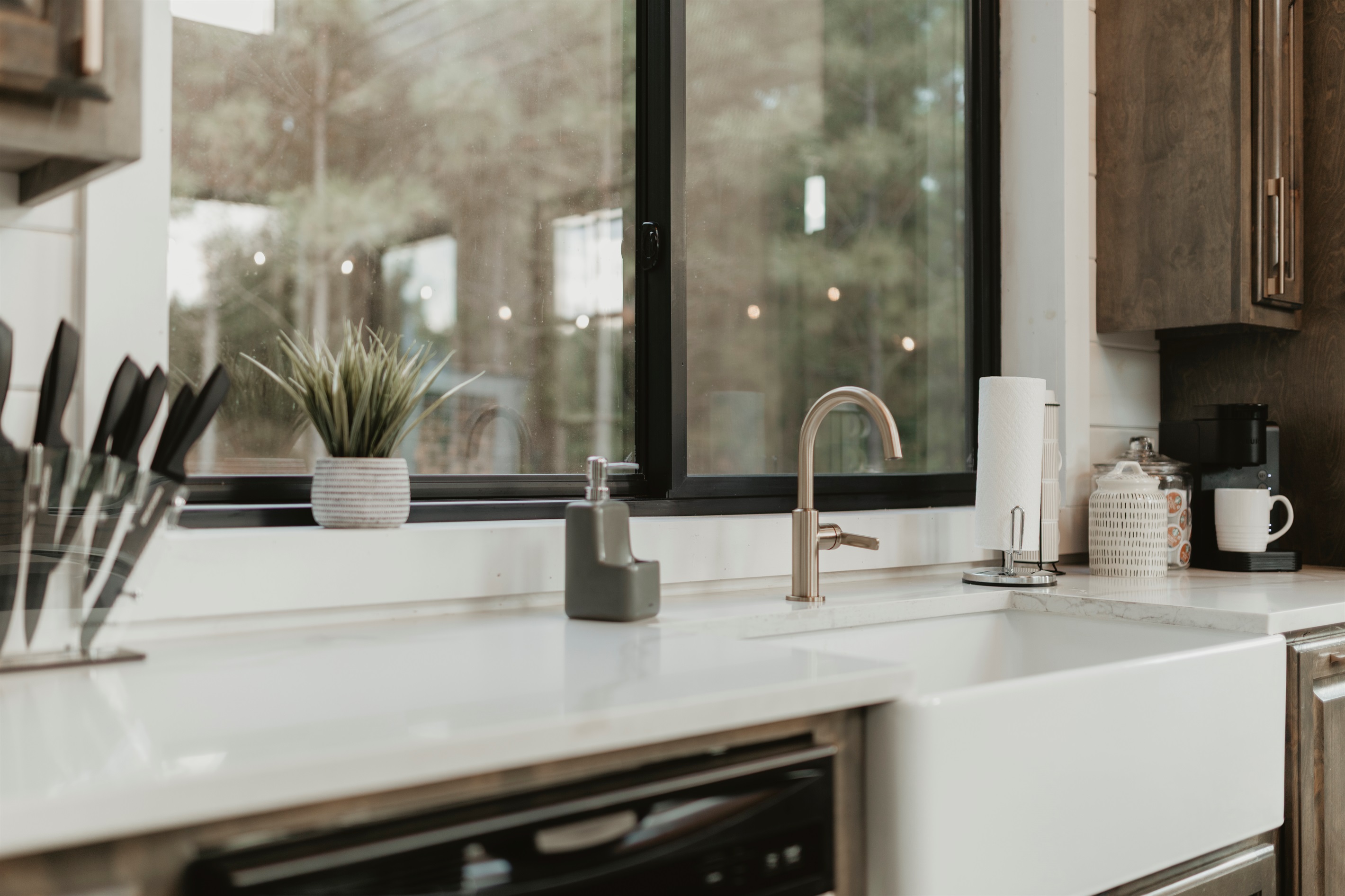 A kitchen with a view—modern farmhouse sink, sleek counters, and forest scenery right outside the window. Whether prepping meals or pouring coffee, every moment feels a little more peaceful here.