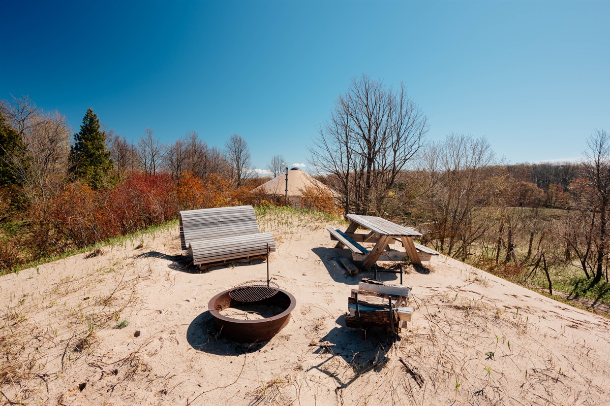 Relax atop the dunes with lounge seating, a picnic table, and a private fire pit overlooking the water and surrounding landscape.