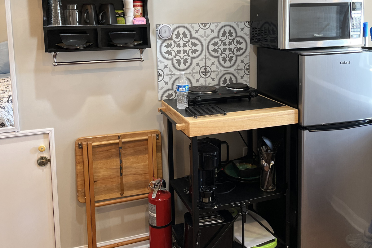 Williams Studio — Kitchenette with a two-burner cooktop, cookware, utensils, and an extra-large mini refrigerator with freezer space.