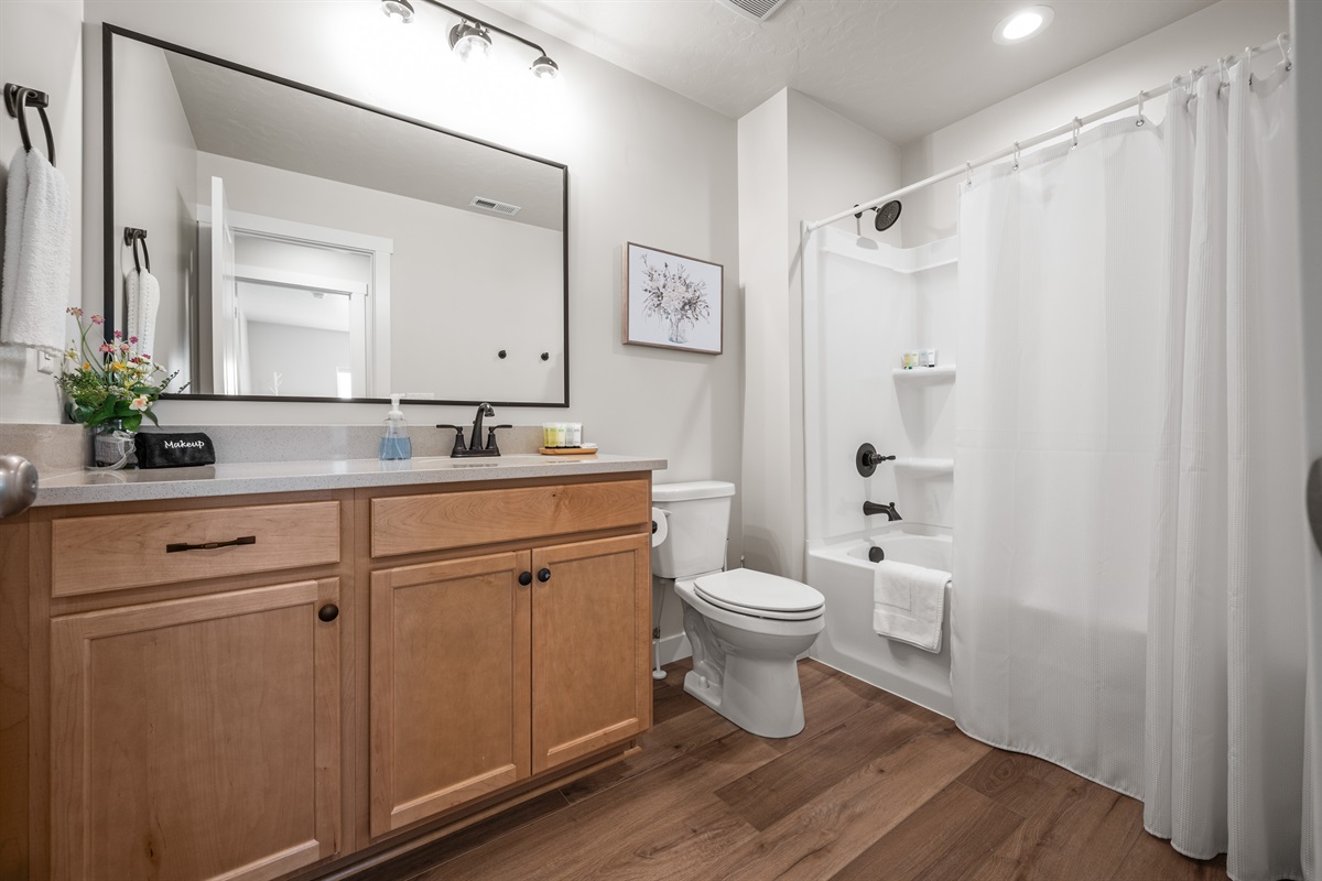 This elegant upstairs bathroom features spacious quartz countertops, a large mirror, recessed lighting, and a tub/shower combo—perfect for a relaxing refresh