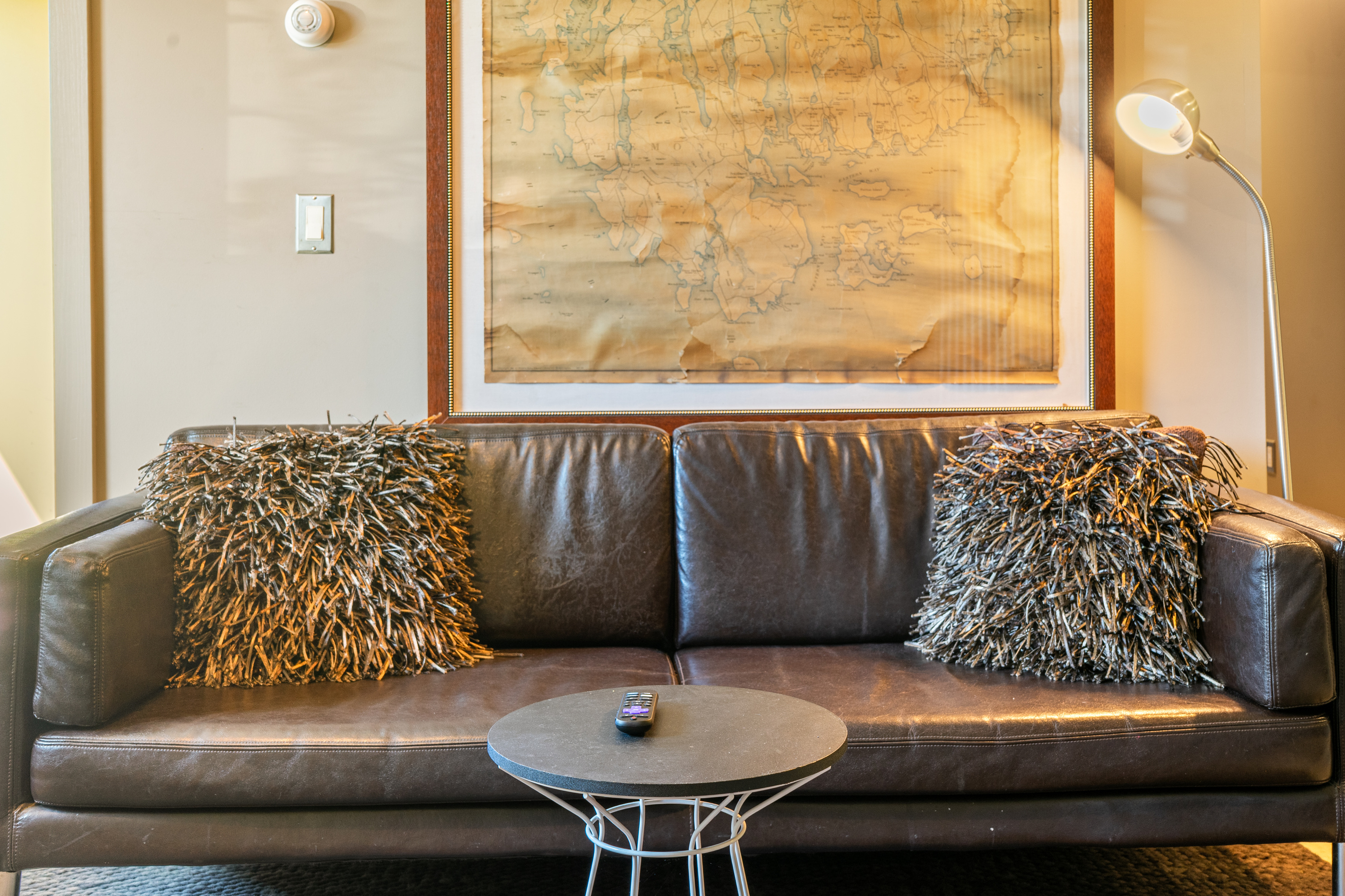 Base Camp relaxation. A rich leather sofa, mid-century accents, and a framed vintage Mount Desert Island map define this cozy lower-level lounge—ideal for unwinding after a day exploring Acadia National Park.