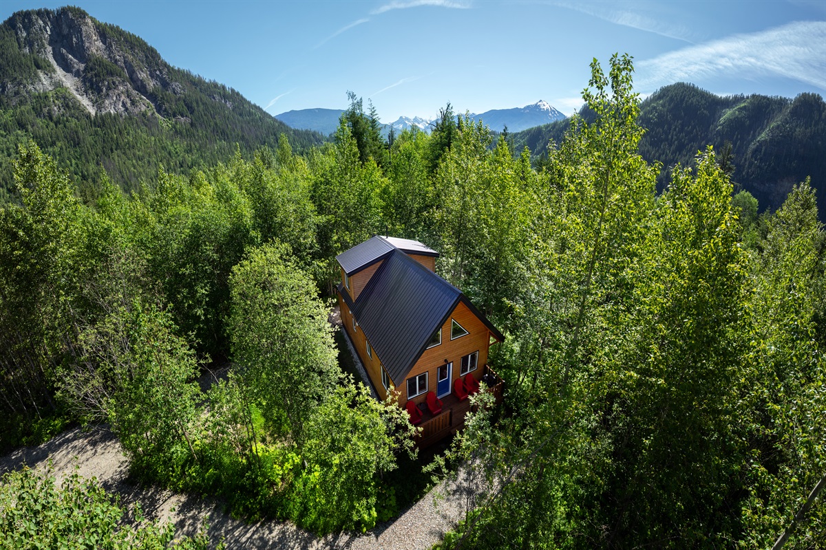 Akira Lodge surrounded by lush landscapes and mountain views. Revelstoke Mountain Resort can be seen in the background.
