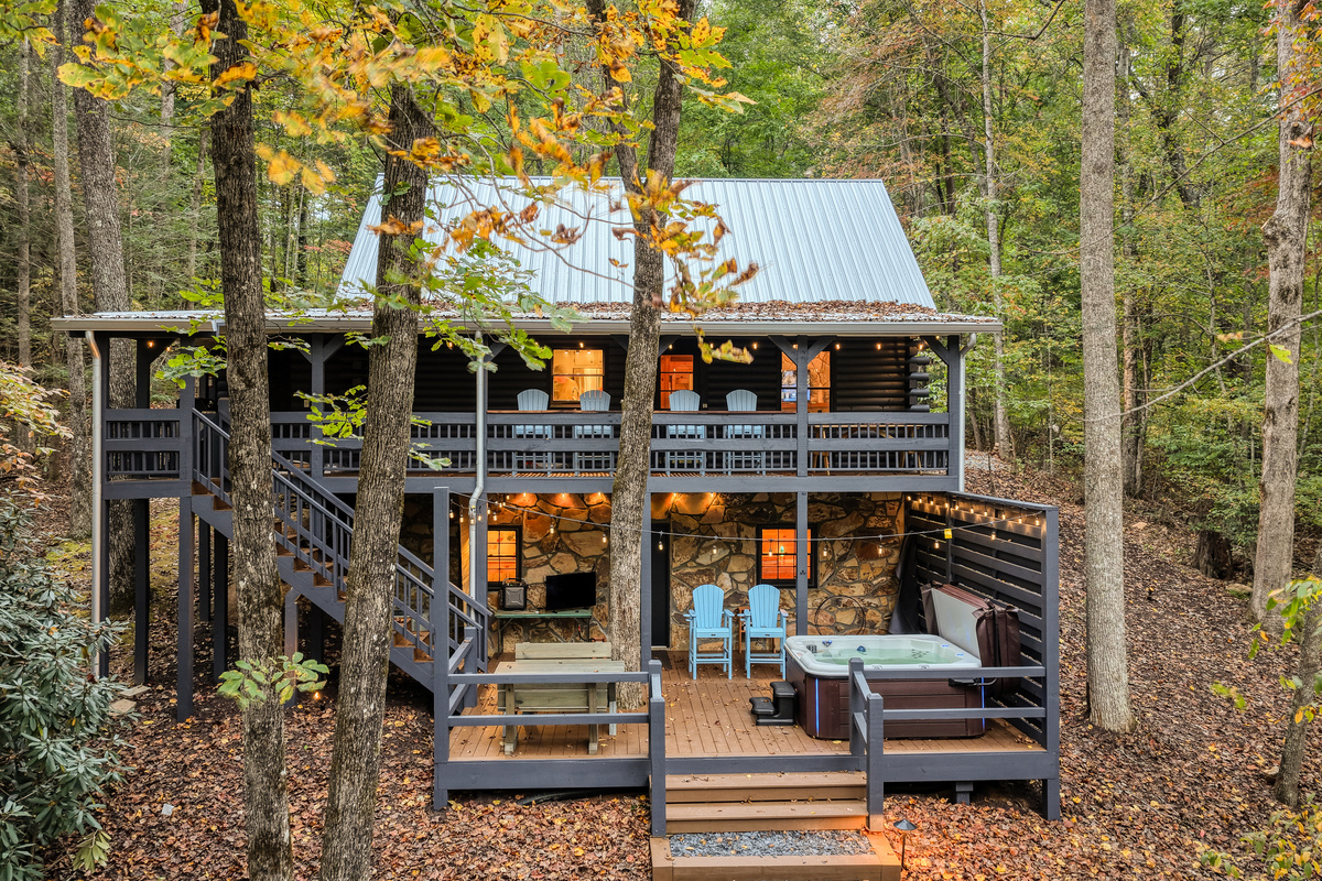 Cabin with a lit deck among the trees.