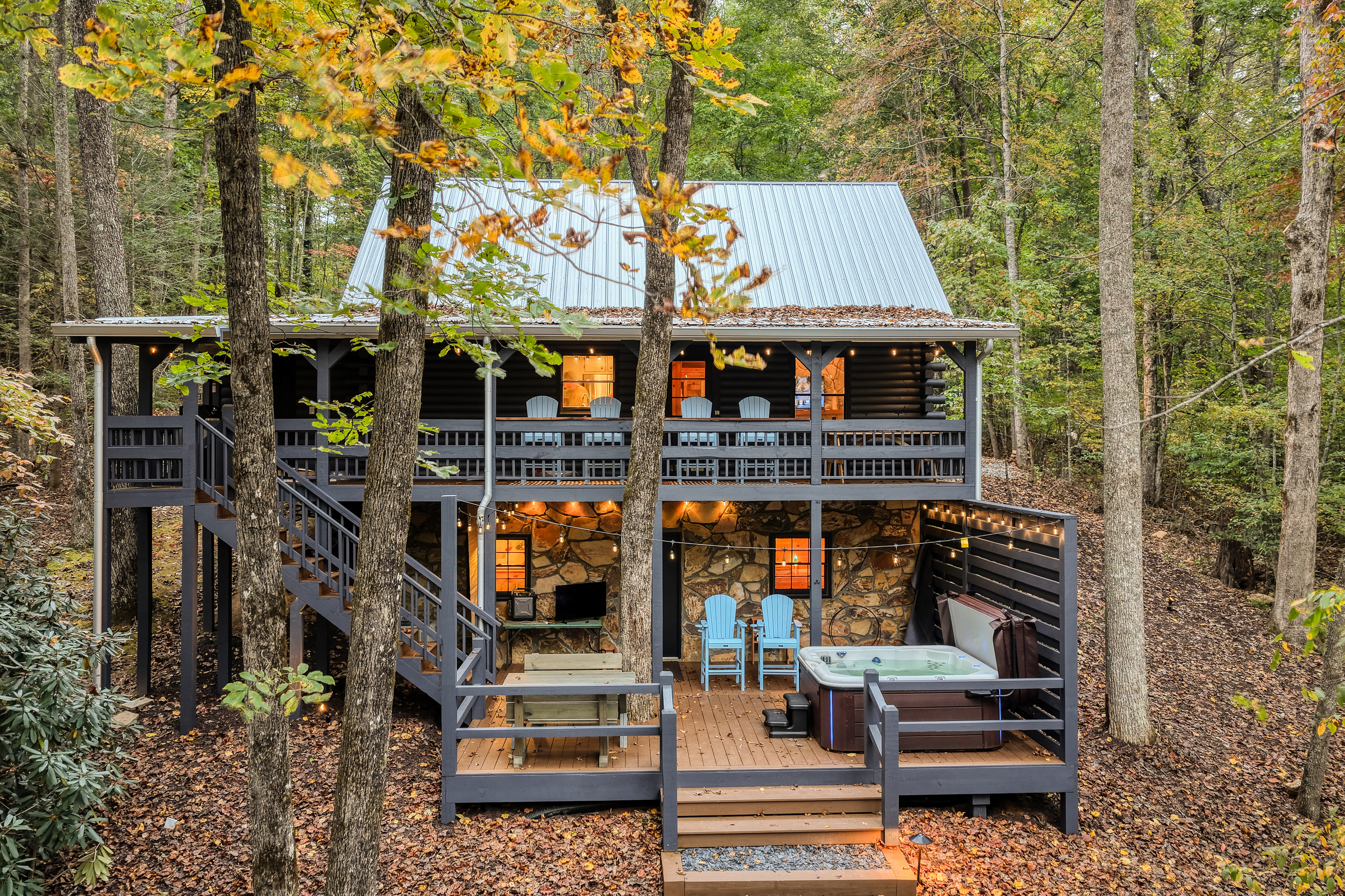 Cabin with a lit deck among the trees.