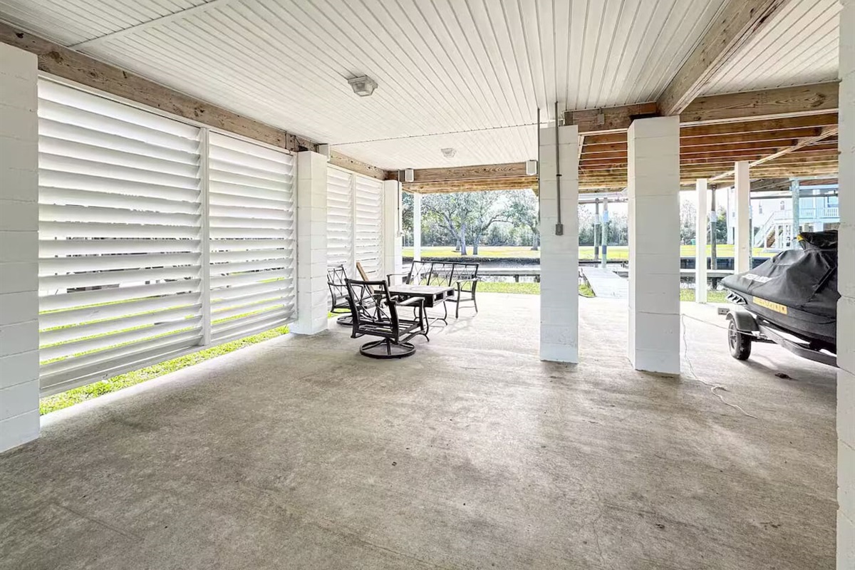 Large shaded patio beneath the home featuring seating space and plenty of room for outdoor hangouts.