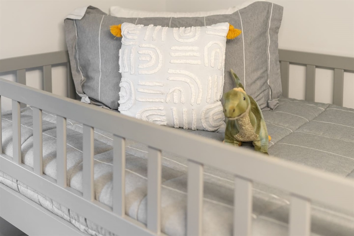 Soft bedding with dinosaur plush and textured pillow add cozy charm.

