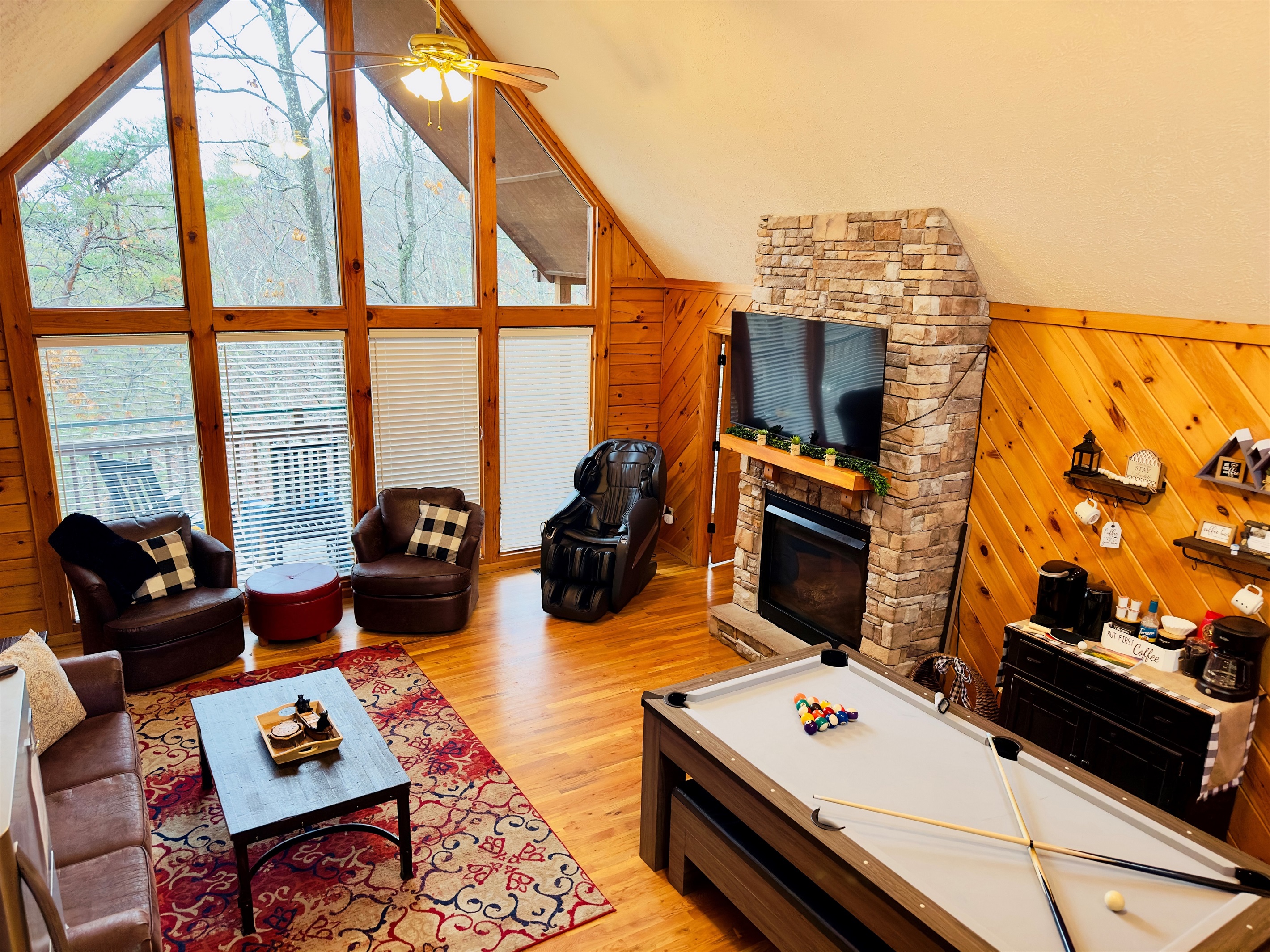 Bright and welcoming family room overlooking the peaceful woods, complete with a large dining table that transforms into a pool table—perfect for family meals, game nights, and memory-making.