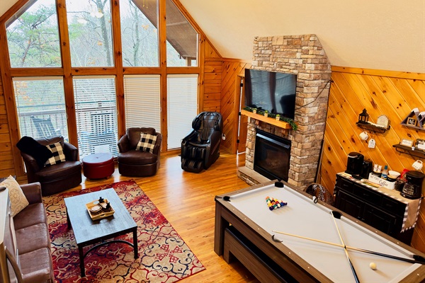 Bright and welcoming family room overlooking the peaceful woods, complete with a large dining table that transforms into a pool table—perfect for family meals, game nights, and memory-making.