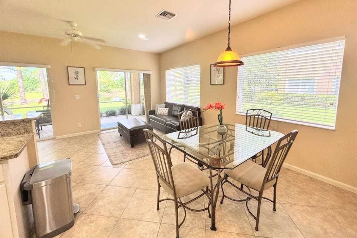 Spacious dining and living area with large windows, natural light, and sliding glass doors leading to the screened patio.