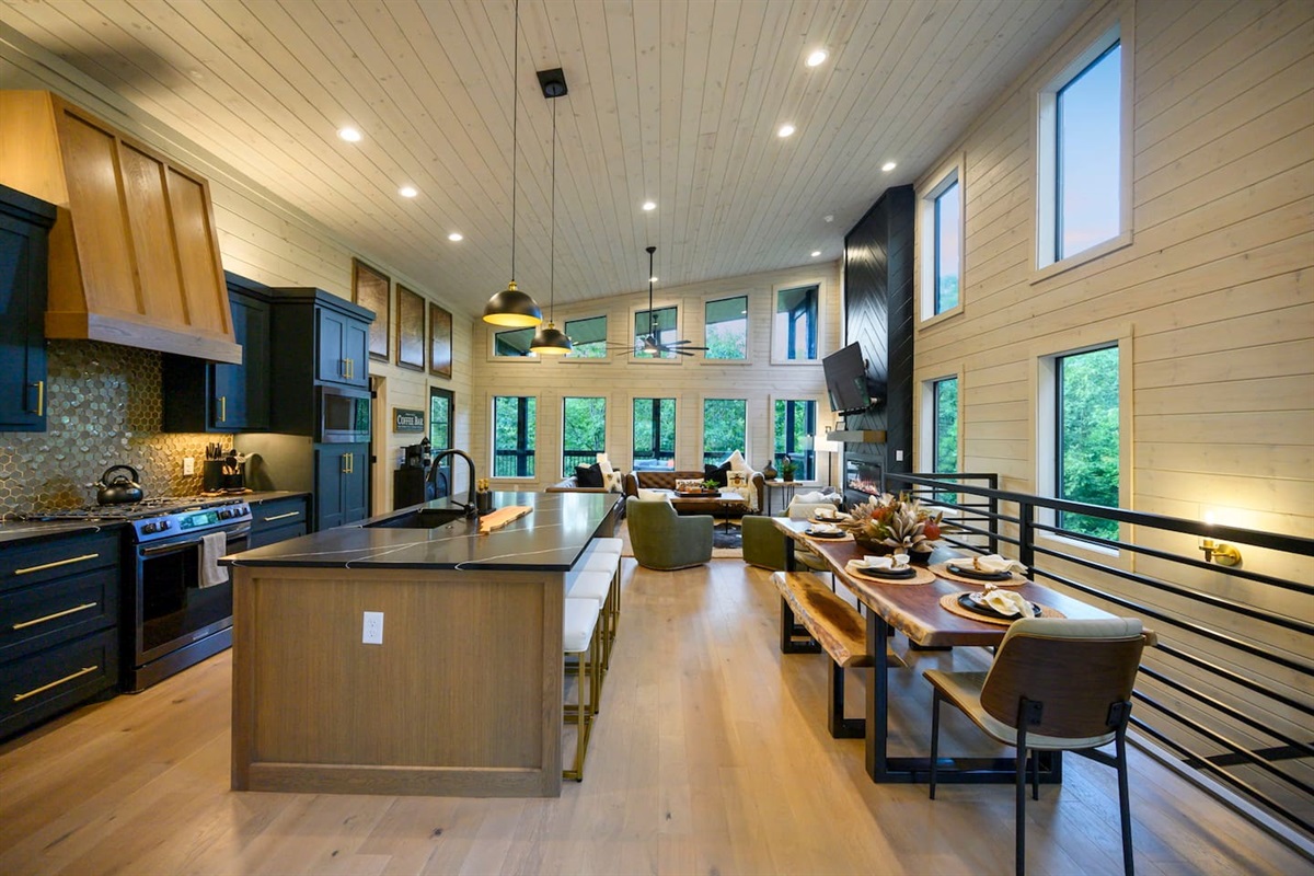 Open kitchen and large island with seating featuring black quartz countertops and gold accents.  The custom built live edge dining table set is big enough to sit up to 8 guests.