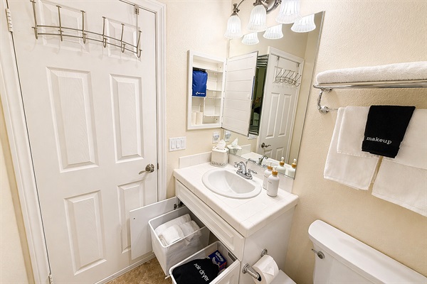 Bathroom vanity with fresh towels, toiletries, and storage