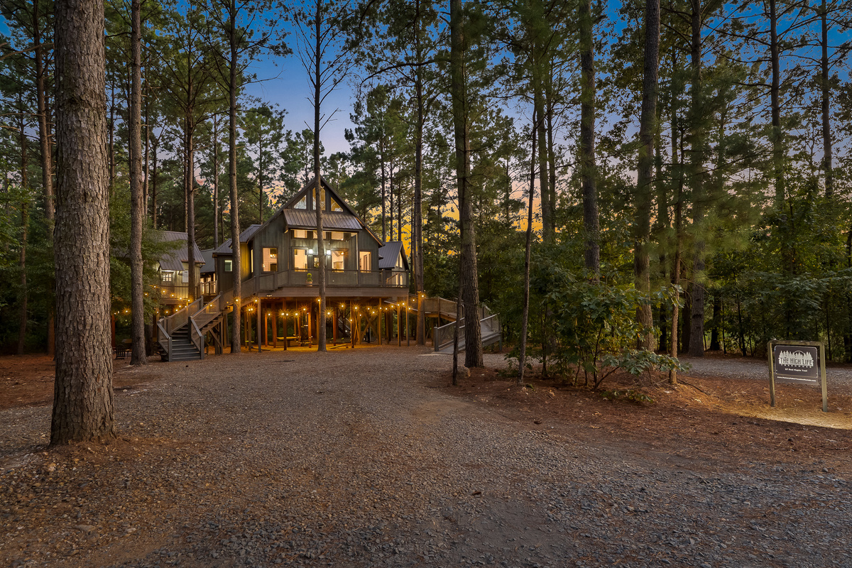 As daylight fades, the entire treehouse begins to glow beneath the pines.
