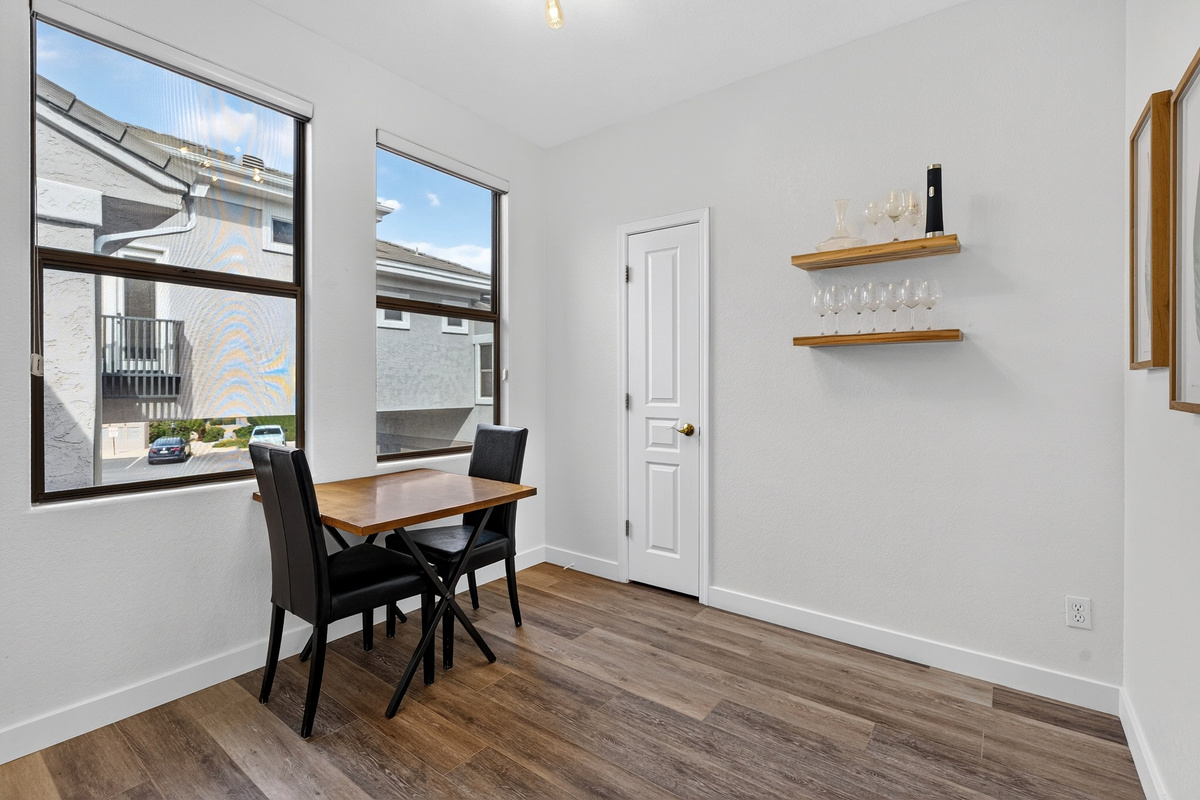 Table seating, window light, and wall shelves for a simple spot to eat, work, or plan the day.