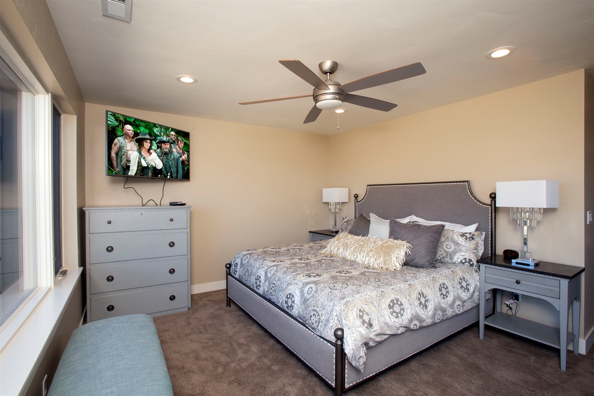 Spacious bedroom with plush bedding and large TV