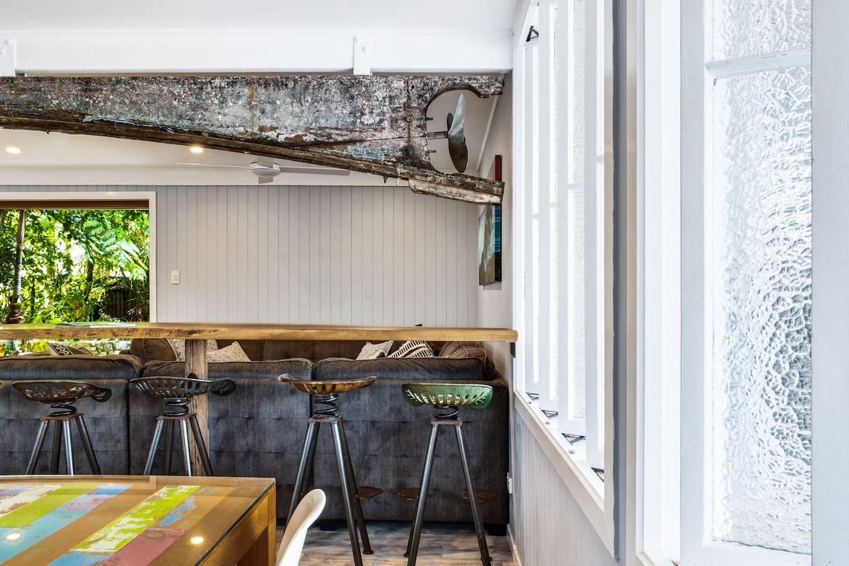 Bar seating connects the downstairs dining and lounge areas at Aaron's Beachside Boat House, creating a casual transition between the home’s shared living spaces.
