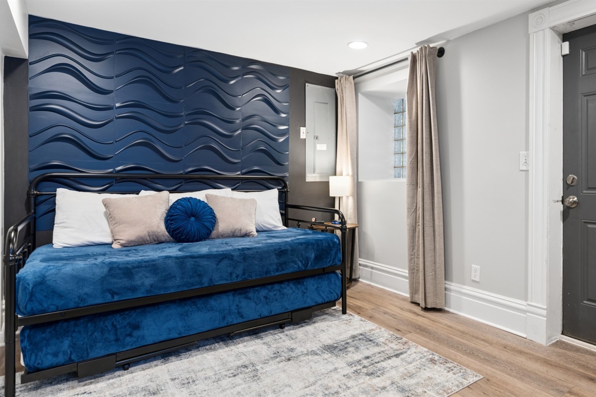 A private basement sleeping space featuring a twin daybed and twin trundle.
