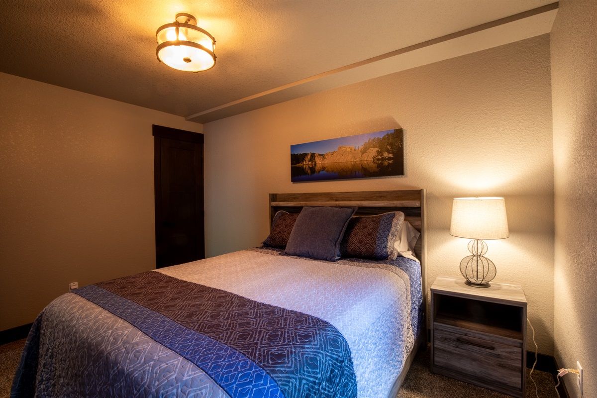 Relax in this cozy lower-level queen bedroom—perfect for guests seeking a quiet, private space to unwind after a full day of Black Hills adventure.