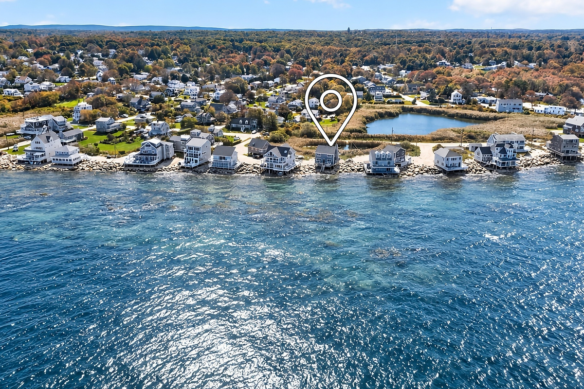 Aerial perspective highlights the sweeping coastline and the home’s prime location near the water.