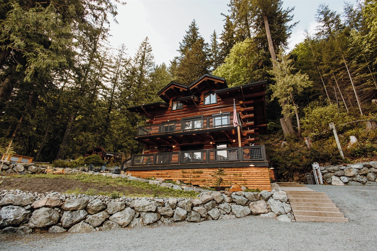 A grand three-story log cabin, seen from the street.