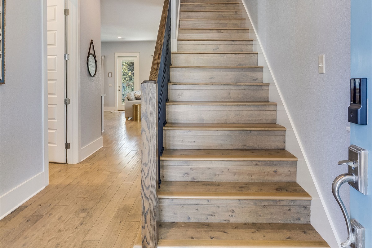 Bright entryway featuring hardwood floors and a modern staircase leading to the upper level.