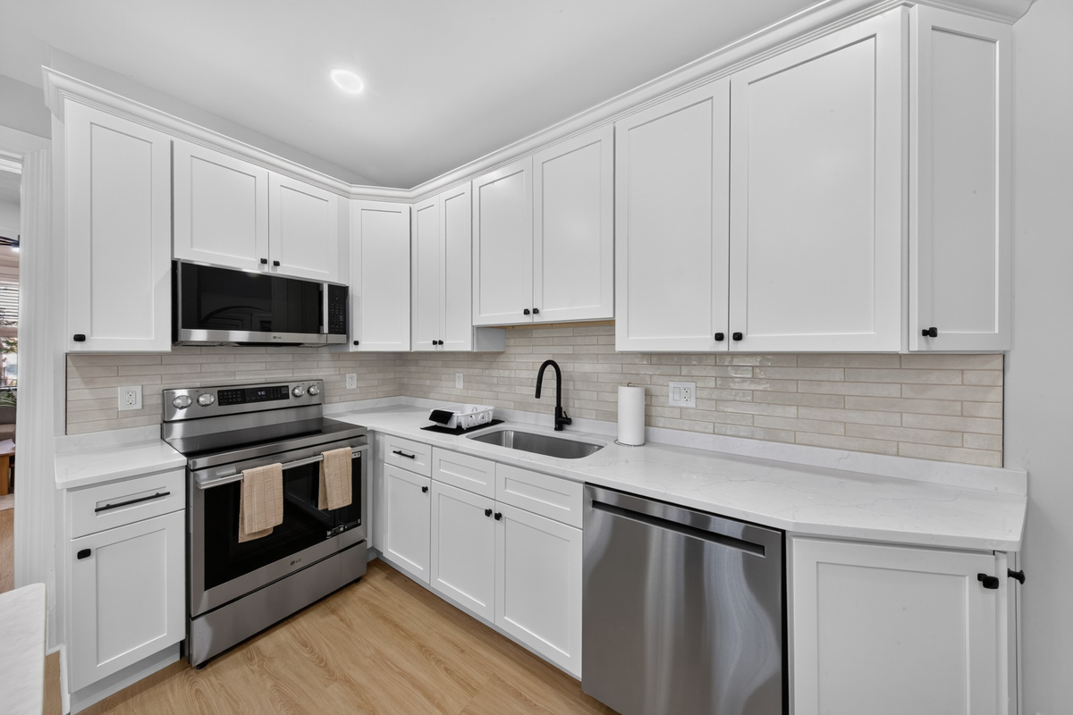 Complete stainless appliance suite including electric range, full refrigerator, microwave, and dishwasher.