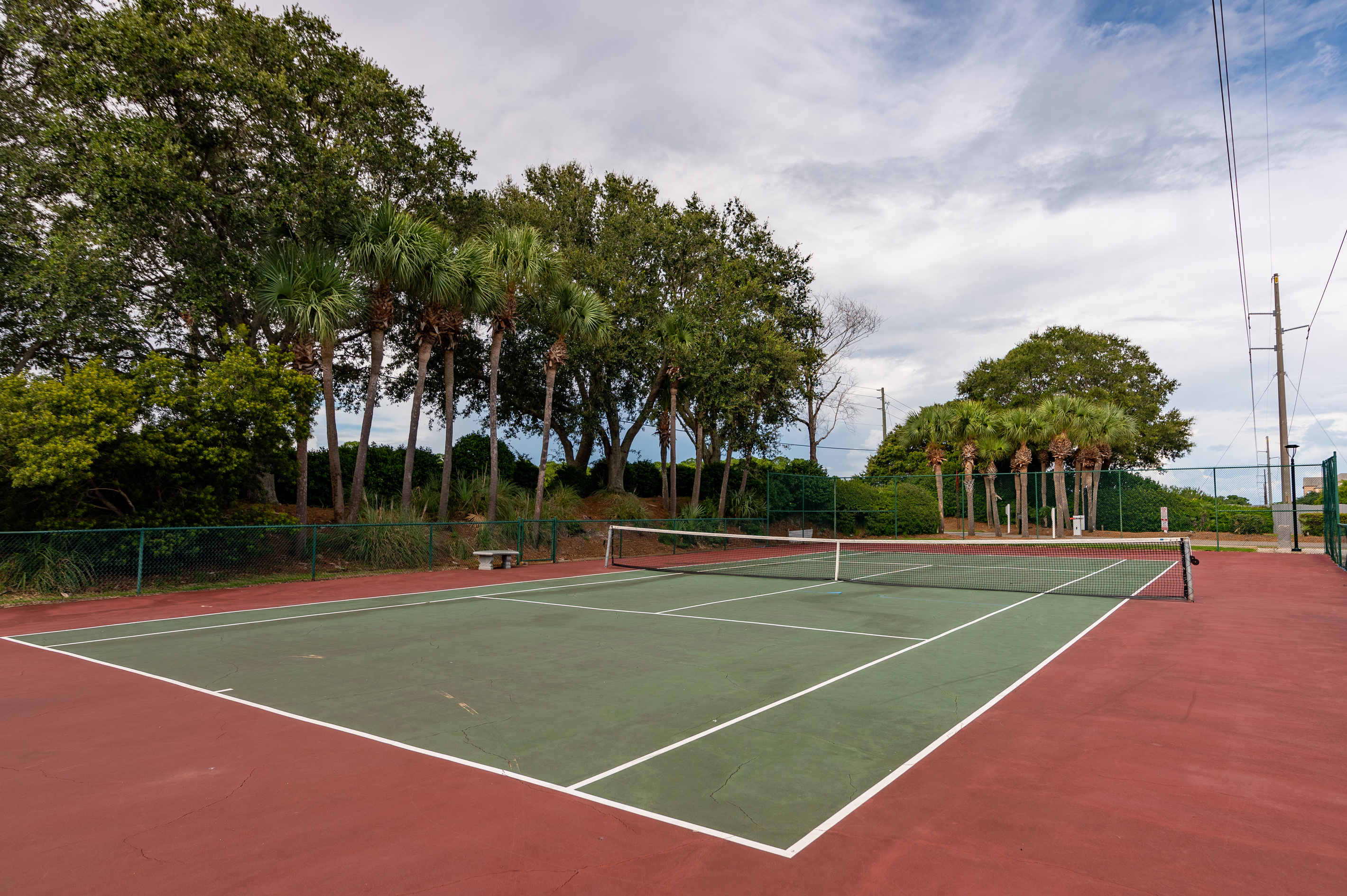 Community tennis court surrounded by lush greenery