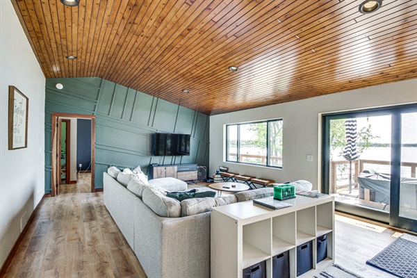 Main living room with lake views, sectional seating, and walkout to deck