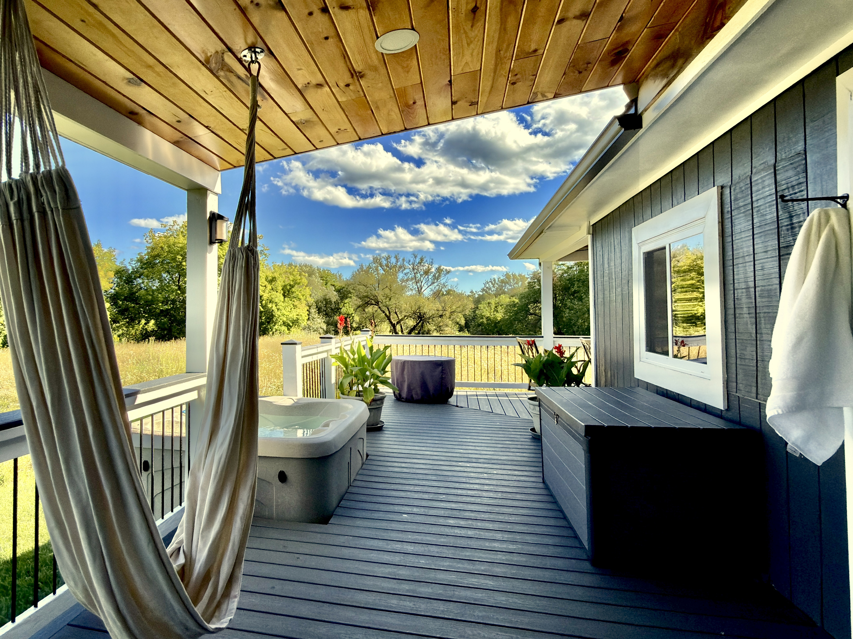 Step out onto the wrap-around porch to find your private hot tub and a relaxing hammock swing. Nestled against a scenic, quiet meadow, this covered outdoor space is designed for slow mornings and peaceful afternoons.