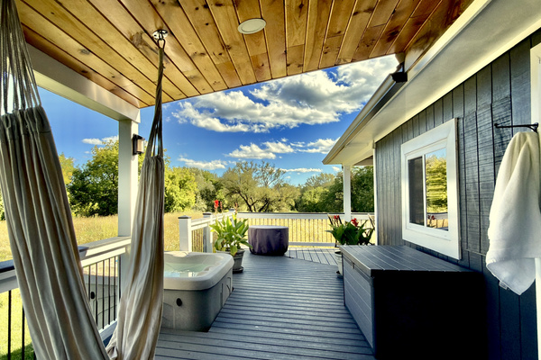 Step out onto the wrap-around porch to find your private hot tub and a relaxing hammock swing. Nestled against a scenic, quiet meadow, this covered outdoor space is designed for slow mornings and peaceful afternoons.