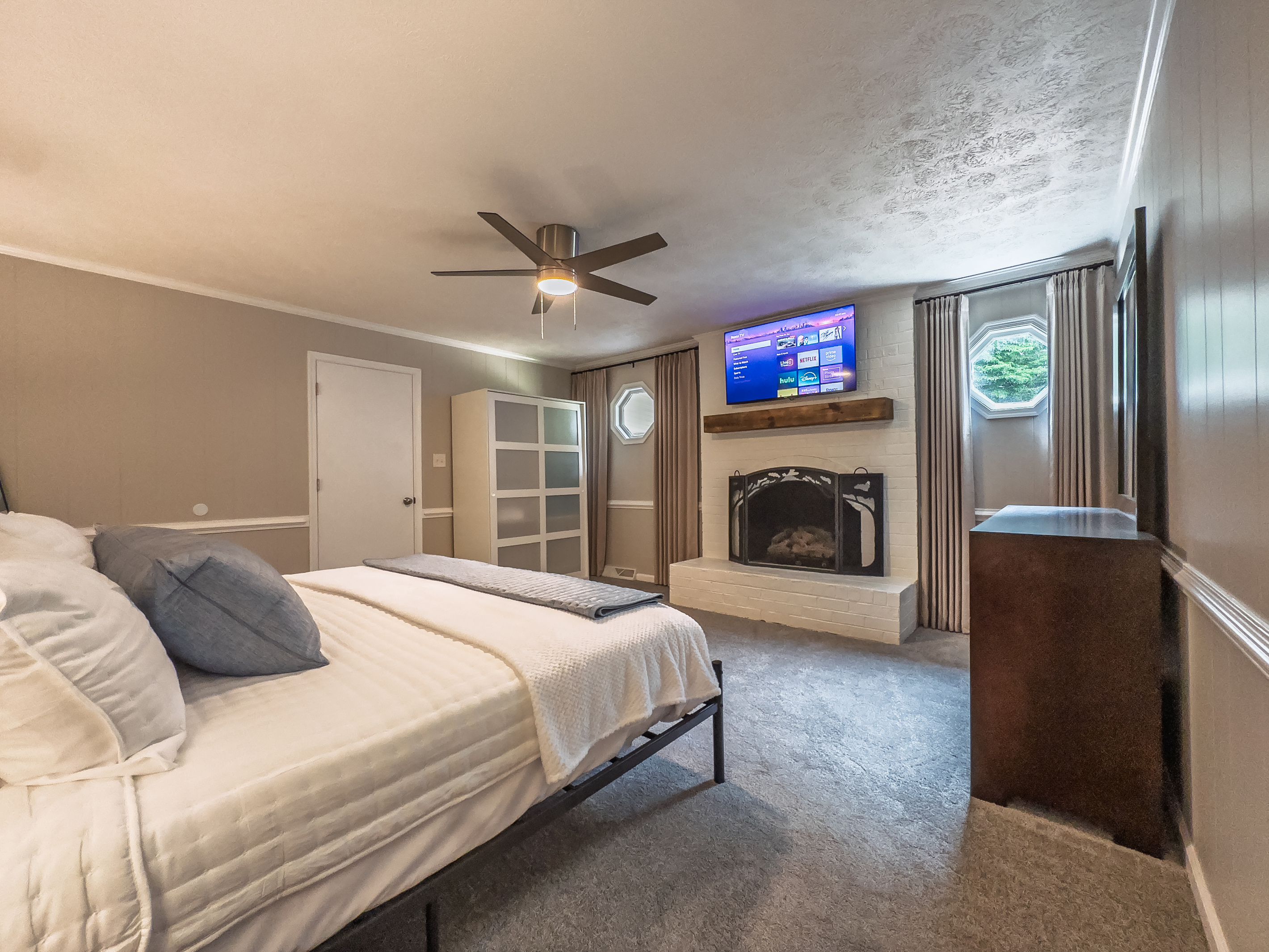 King bed, 55" Smart TV, ceiling fan, two led light nightstands with multiple charging ports, two multi light function lamps, blackout curtains, dresser, wardrobe closet, full length mirror, stylish brick fireplace - not in use.