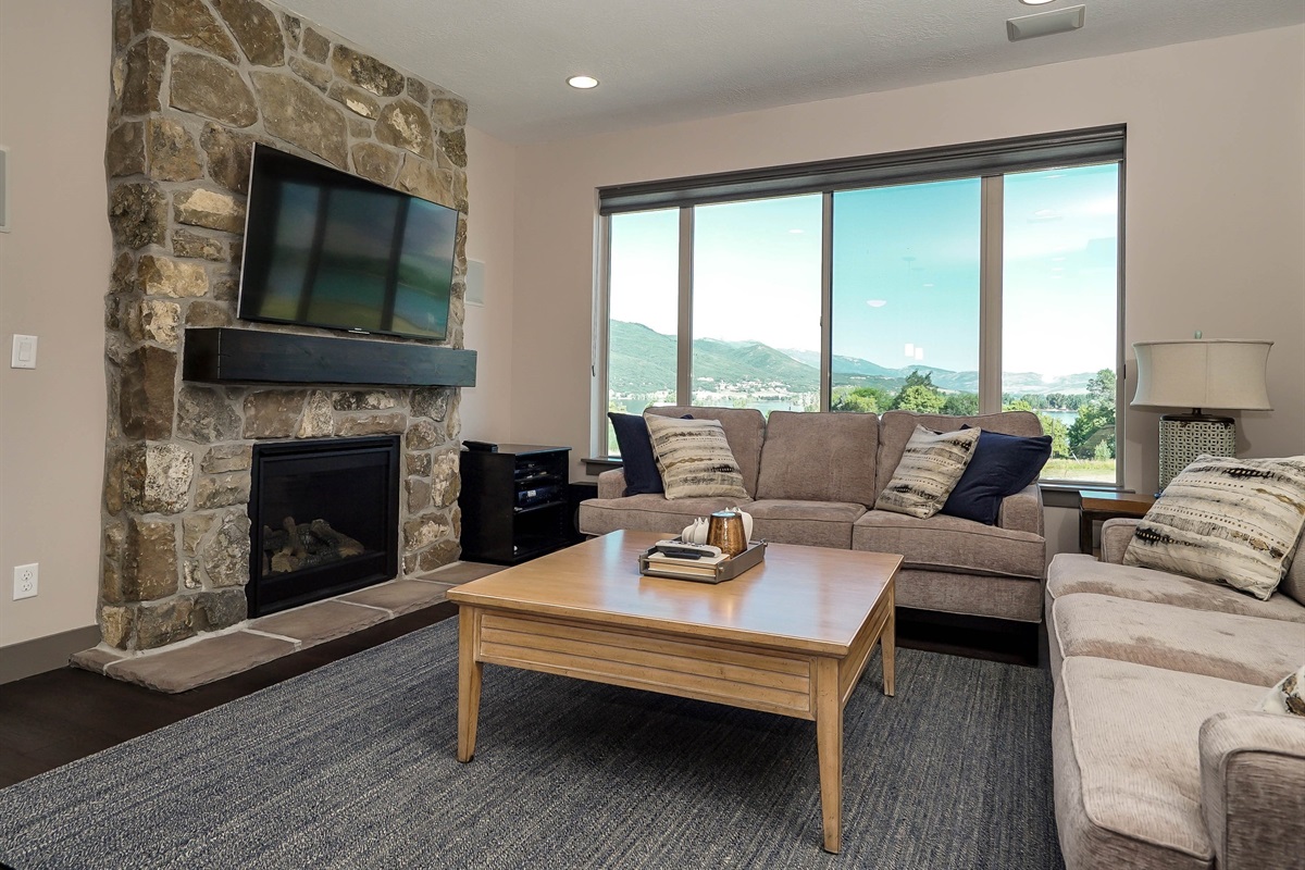 Main level living room with stone fireplace and large windows.